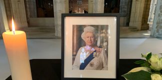 Queen Elizabeth II photo withlarge candle and flower in church